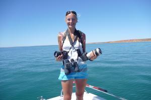 Lady standing holding cameras on a boat in the sea