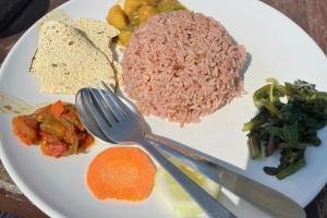 a plate, with knife and fork, including a portion of pink rice