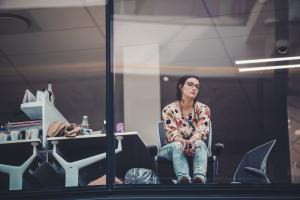 Woman looking sad through glass window of office building 