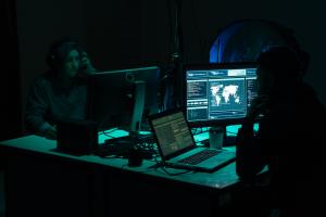 Two people sitting in front of computer screens in a dark room