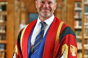 Photo of Mr Steve Backshall in Bangor University library in graduation gown