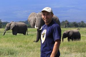 Dr Graeme Shannon gyda thri eliffant yn y cefndir