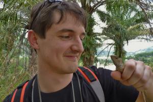 Dr James Hicks looking at a lizard he is holding in his hand