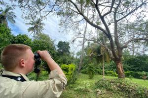Patrick Allsop looking at trees through binoculars
