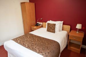 View of Single Room with White bedding one cupboard, night stand with a light