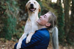 Woman Carrying Adult Fawn Dog in a forrest
