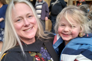 Person at graduation ceremony holding a young child