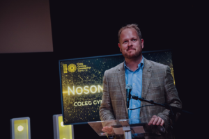 Photo of Dr Llŷr Roberts at a loectern in an awards ceremony