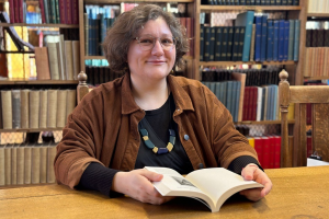 Person sitting in a library holding a book