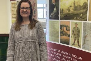 Dr Lowri Ann Rees stands in front of an Institute for the Study of Welsh Estates banner