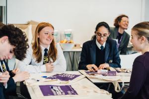 Group of students in school uniform working around a table.
