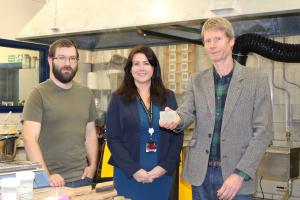 Three people looking at the camera in a lab with one person holding a bar of soap