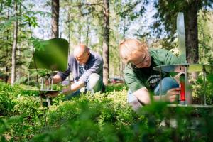  two people with  ground level contraptions in a wooded setting