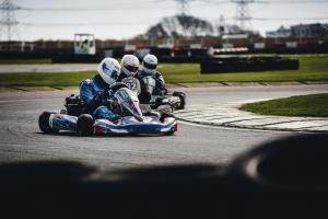 A go karting track with three individuals racing in go karts.