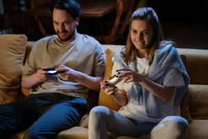 Students sitting on sofa with controllers playing a video game.