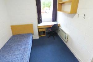 Ffriddoedd classic ensuite room 8.9ms with a bed, desk, chair and shelves