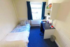 St Mary's Large budget single room with a bed, desk, chair and shelves