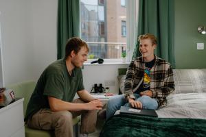  Two students sitting in a room in St Mary's halls playing a card game.