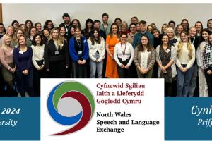 Mae grŵp o bobl yn sefyll ac yn gwennu i'r camera. Mae'r testun ar y llun yn dweud 'Cynhadledd Cyfnewid Sgiliau Iaith a Lleferydd Gogledd Cymru 2024 Prifysgol Wrecsam'