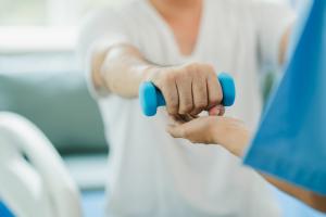 Person having rehabilitation holding a weight with an outstretched arm
