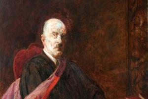 Academic sitting in a chair in a gown 