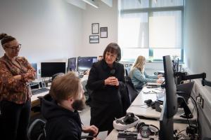Secretary State for Wales speaking to person sat next to desk with big screen