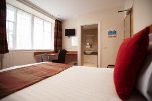 bright room with a single bed with a view on a desk and door open to bathroom with big window and lots of natural light