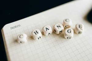 Notes paper with 7 white dice spelling out CHANGE