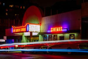 Kew Gardens Cinema in neon lights in the evening with strobe light traffic passing
