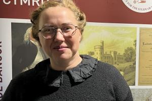 Photograph of doctoral researcher Daisy standing in front of an ISWE banner