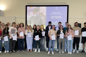 A large group of students standing holding their certificates for learning Welsh