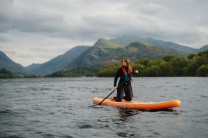 Myfyriwr yn padlfyrddio ar ei gliniau ar Lyn Padarn, Llanberis.
