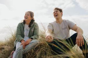 Two students sitting, laughing in the dunes
