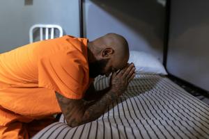 American Prisoner praying on a bed