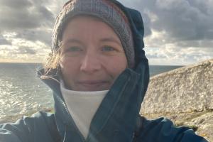 Svenja standing on the coast with a cliff and the sea behind