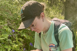 Charlotte Bendell next to some flowers, measuring something