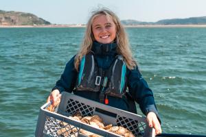 Rhianna Parry on a boat, holding a crate of crabs