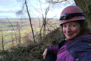 Luci Kirkpatrick in a hard hat sitting under a tree 