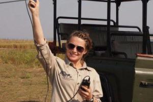 Rhea Burton holding a radio antenna in the African savannah