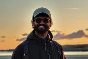 Joe Roy standing on a beach with the sunset behind him