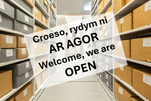 Sign saying: Welcome we are open against an archives backdrop