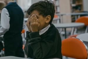 A Boy Covering His Face with His Hands