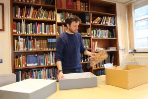 Photograph of Alex in the archives unboxing archival material 