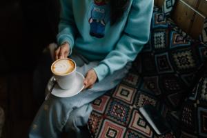 Image of a person sat on a sofa with a cup of coffee