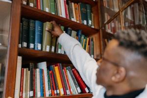 Image of someone reaching for a book on a bookshelf