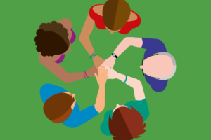 An image looking down at 5 people standing in a circle facing each other with their hands joined in the middle