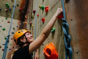 A student is climbing the climbing wall at Canolfan Brailsford