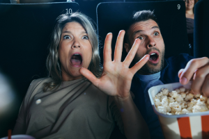 Two people at the cinema with popcorn obviously scared watching a scary movie