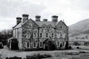 Black and white photograph of a country house in a mountainous landscape