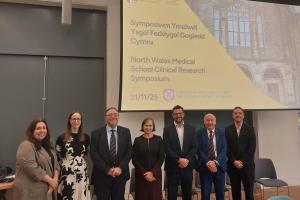 People standing in a group with a power point screen behind them